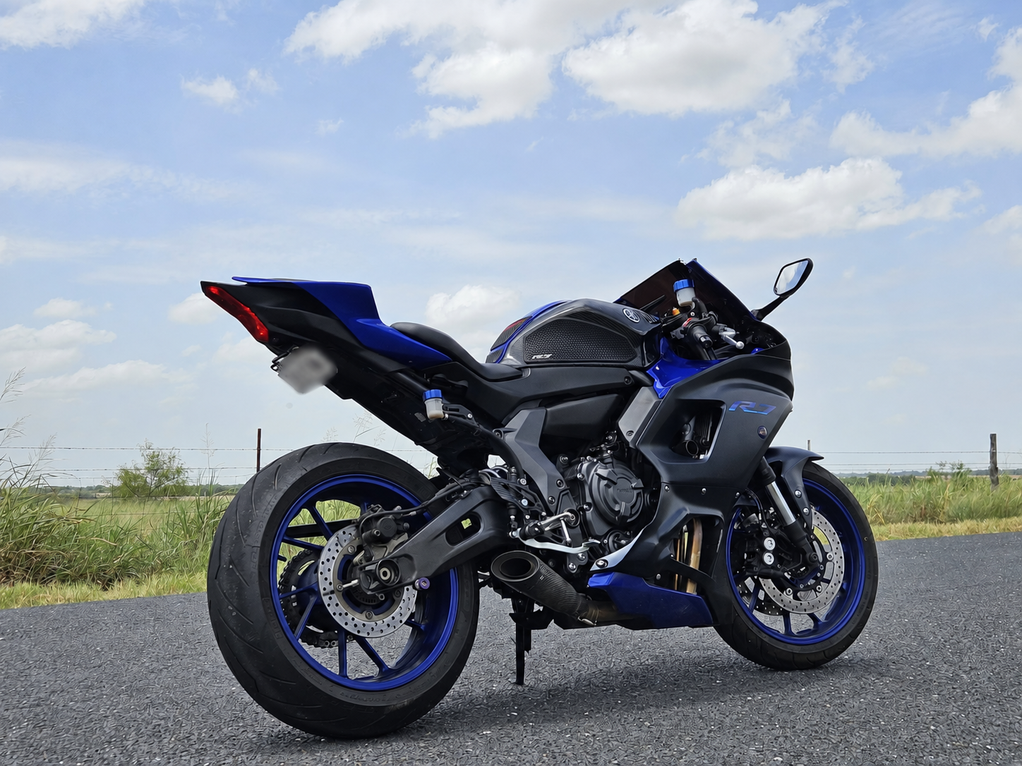 Blue and black 2023 Yamaha R7 parked beside a rural road